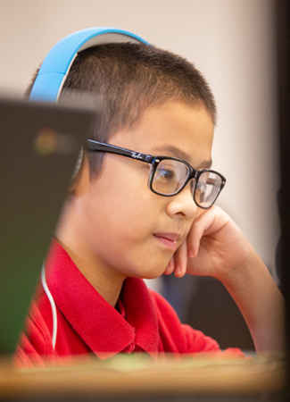 Photo: Student with headphones looking at computer